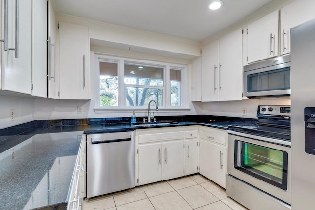 kitchen featuring sink, light tile patterned floors, ornamental molding, appliances with stainless steel finishes, and white cabinetry