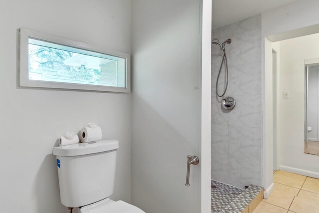 bathroom featuring tile patterned flooring, toilet, and tiled shower