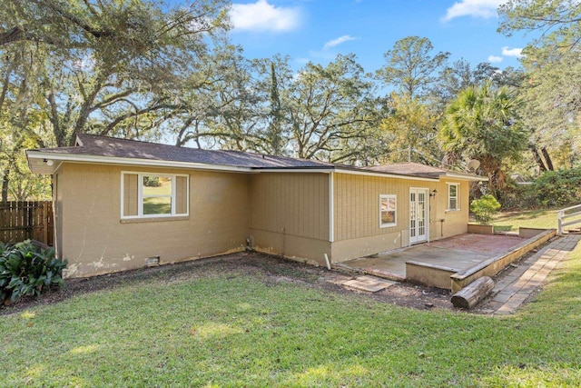 rear view of property featuring a lawn, a patio area, and french doors