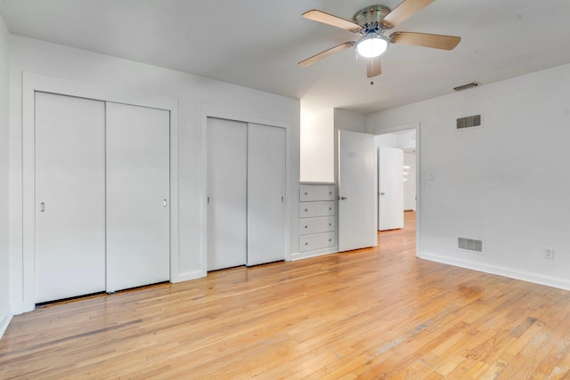 unfurnished bedroom with ceiling fan, light hardwood / wood-style floors, and two closets