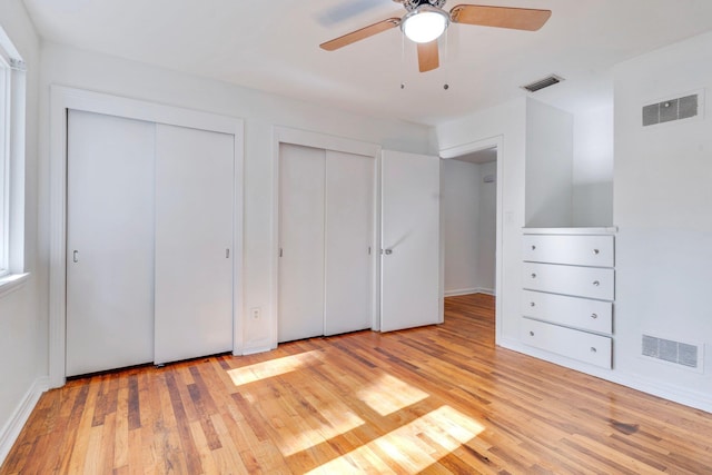 unfurnished bedroom featuring light hardwood / wood-style floors, ceiling fan, and multiple closets