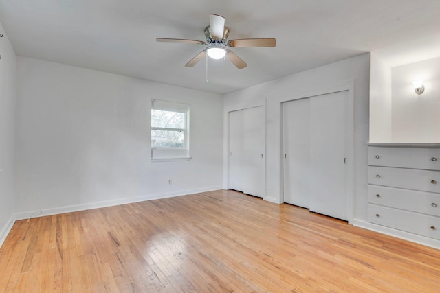 unfurnished bedroom featuring ceiling fan, light hardwood / wood-style floors, and two closets