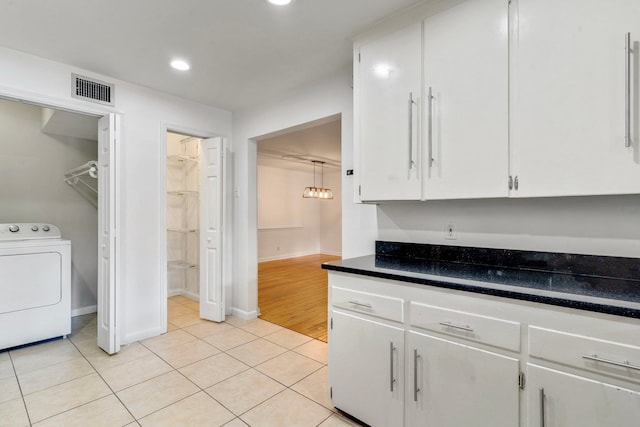 kitchen featuring washer / dryer, white cabinetry, and light tile patterned floors