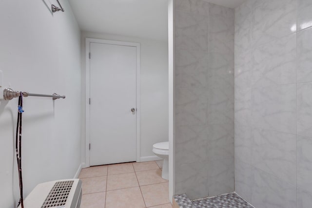 bathroom with tile patterned flooring, toilet, and a tile shower