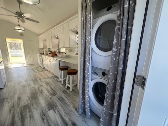 laundry area with hardwood / wood-style flooring, stacked washer / drying machine, and ceiling fan