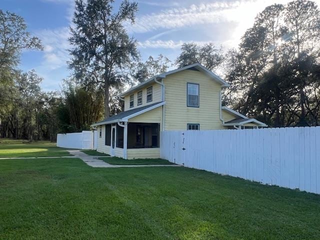 rear view of house with a yard and a sunroom