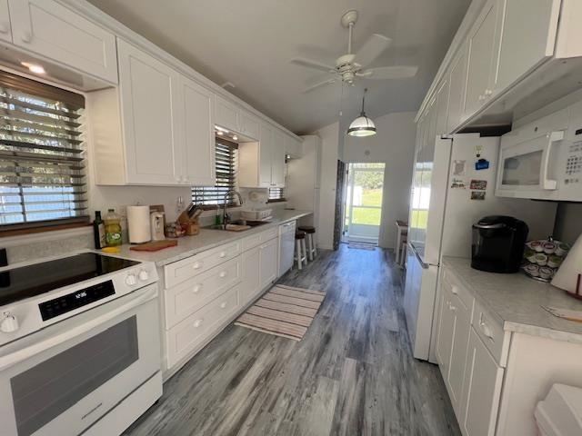 kitchen featuring white appliances, wood-type flooring, sink, and white cabinets