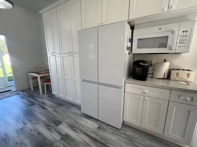 kitchen featuring white appliances, light hardwood / wood-style flooring, and white cabinets