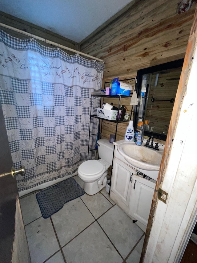 bathroom featuring vanity, tile patterned floors, wooden walls, toilet, and curtained shower