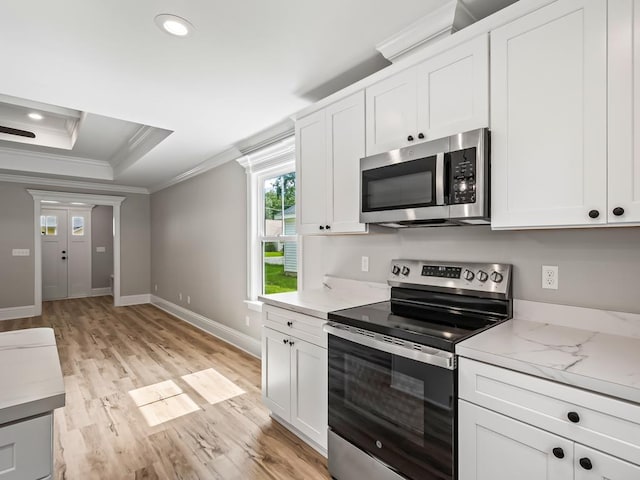 kitchen featuring crown molding, light hardwood / wood-style flooring, appliances with stainless steel finishes, a tray ceiling, and white cabinets