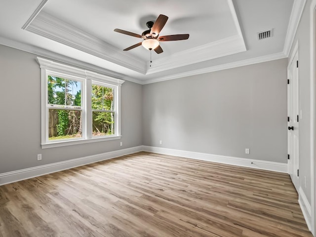 spare room featuring a raised ceiling, crown molding, wood-type flooring, and ceiling fan