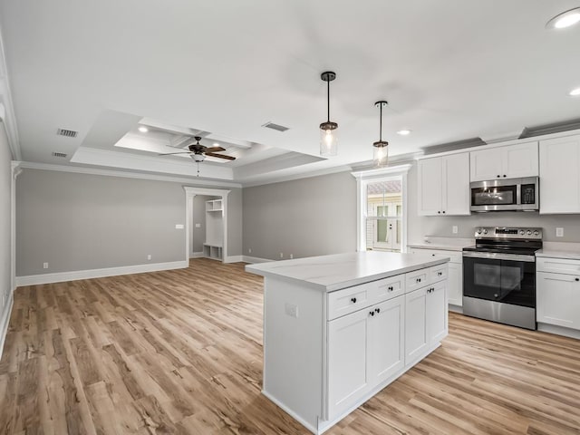 kitchen with crown molding, appliances with stainless steel finishes, a tray ceiling, white cabinets, and decorative light fixtures