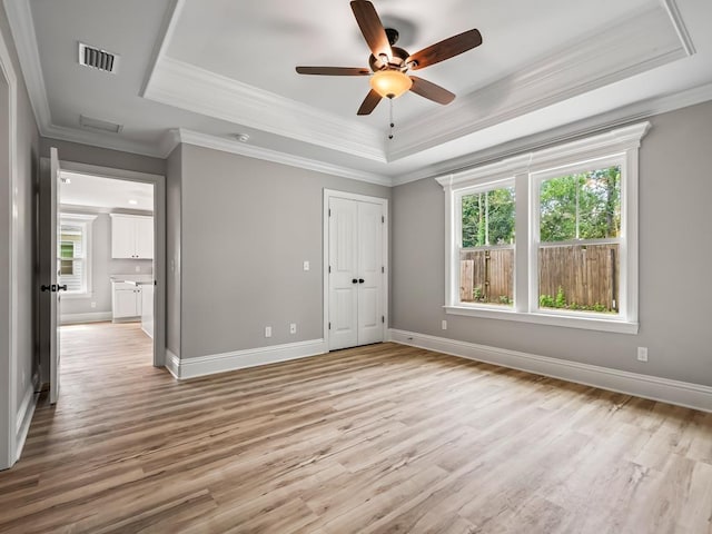 unfurnished bedroom with multiple windows, crown molding, ceiling fan, and a tray ceiling