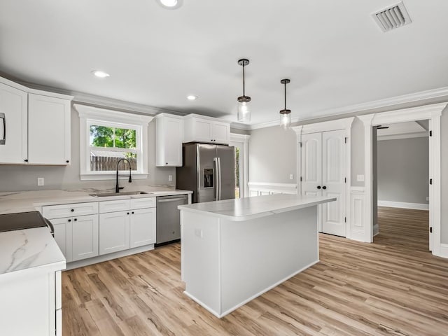 kitchen featuring pendant lighting, sink, appliances with stainless steel finishes, a center island, and white cabinets