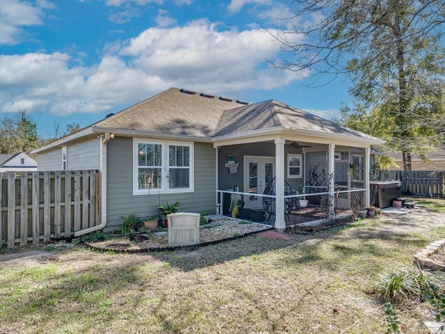 rear view of property with a yard, a hot tub, and a sunroom