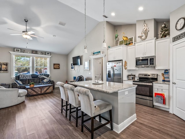 kitchen with white cabinetry, stainless steel appliances, a center island, decorative light fixtures, and a kitchen breakfast bar