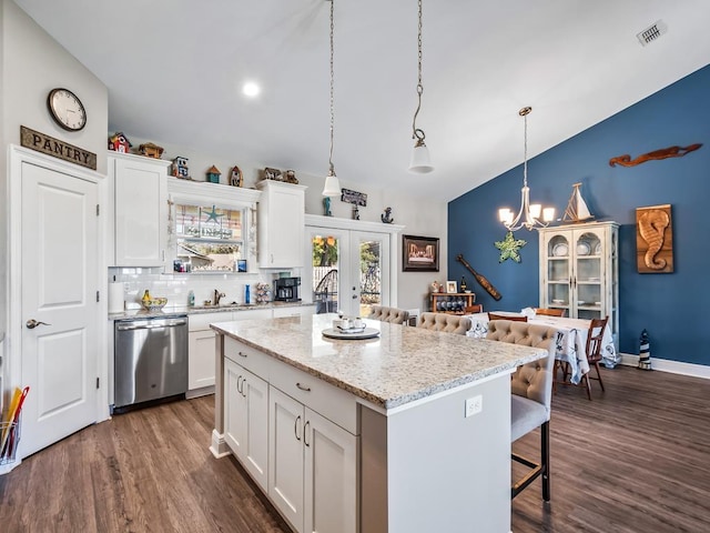 kitchen with dishwasher, light stone countertops, pendant lighting, a kitchen island, and white cabinetry