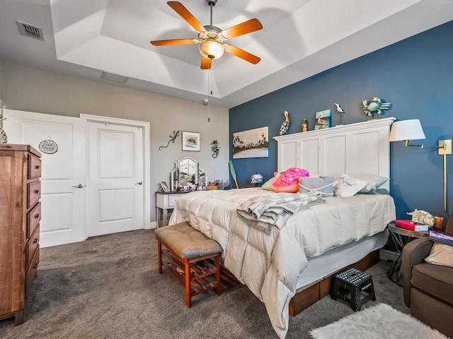 bedroom featuring dark carpet, ceiling fan, and a tray ceiling