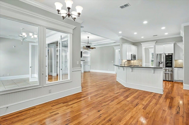 kitchen featuring stainless steel appliances, a ceiling fan, dark countertops, a chandelier, and light wood finished floors