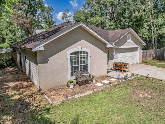 51 Mulberry Cir, Crawfordville, FL 32327 - view of home's exterior featuring concrete driveway, roof with shingles, stucco siding, an attached garage, and a chimney