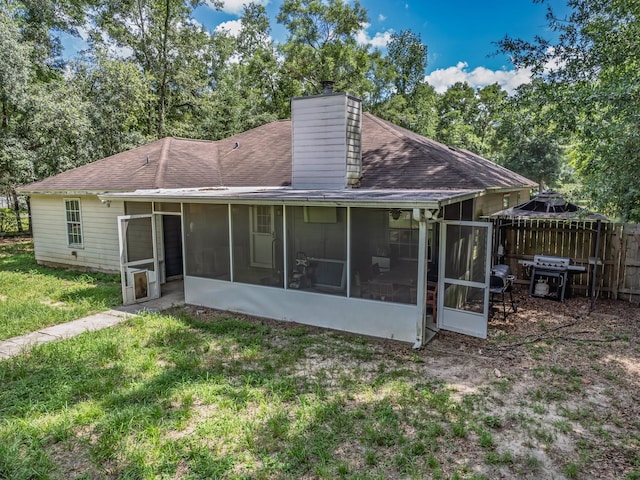 51 Mulberry Cir, Crawfordville, FL 32327 - back of house featuring a sunroom, a chimney, roof with shingles, and view of scattered trees