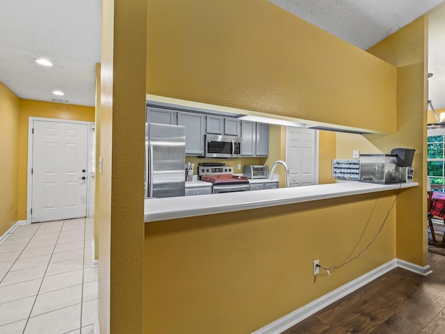 51 Mulberry Cir, Crawfordville, FL 32327 - kitchen with stainless steel appliances, a peninsula, light wood-style flooring, gray cabinetry, and light countertops