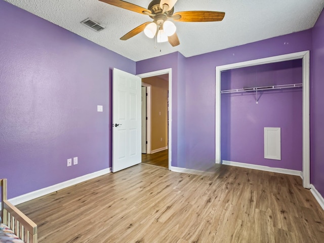 51 Mulberry Cir, Crawfordville, FL 32327 - unfurnished bedroom with wood finished floors, a ceiling fan, a closet, and a textured ceiling