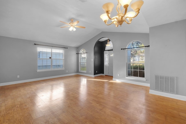 unfurnished living room with arched walkways, vaulted ceiling, light wood-type flooring, and visible vents