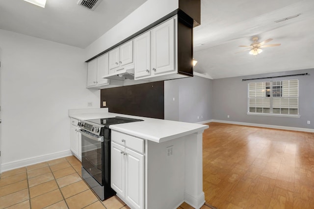 kitchen featuring electric stove, light countertops, open floor plan, white cabinetry, and wallpapered walls