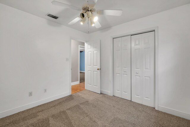 unfurnished bedroom featuring baseboards, visible vents, a closet, and light colored carpet