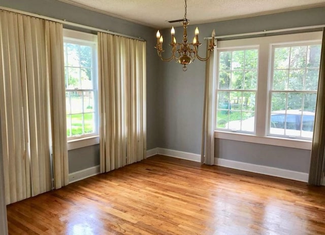 unfurnished room with hardwood / wood-style floors, a textured ceiling, and an inviting chandelier