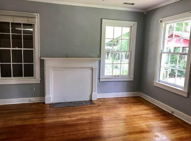 unfurnished living room with a healthy amount of sunlight, hardwood / wood-style flooring, and crown molding