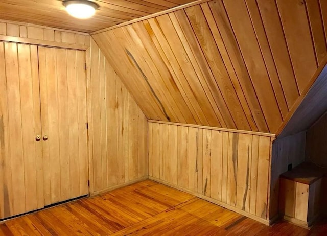 bonus room featuring wood walls, light hardwood / wood-style floors, wooden ceiling, and vaulted ceiling