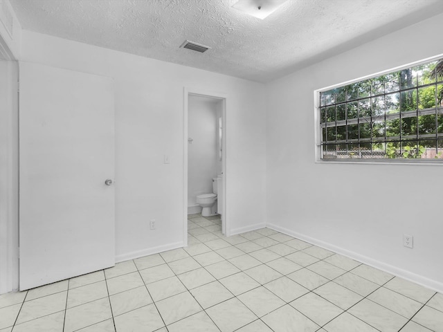 unfurnished bedroom featuring a textured ceiling and ensuite bath