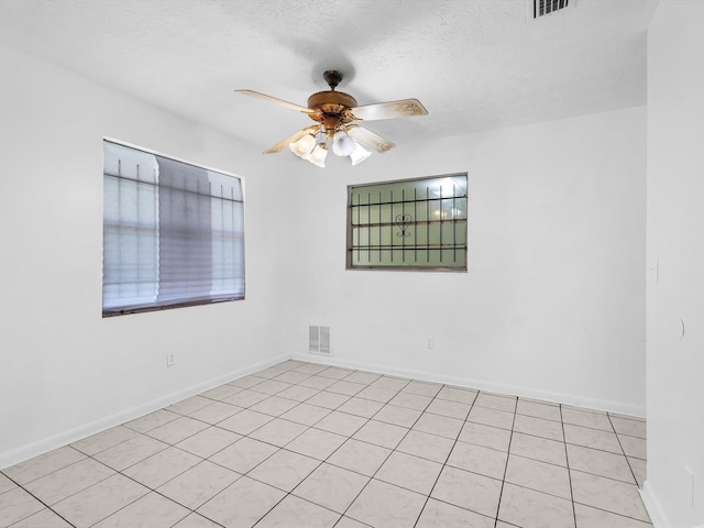 tiled spare room with a textured ceiling and ceiling fan