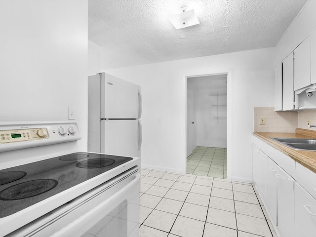 kitchen featuring light tile patterned flooring, backsplash, a textured ceiling, white appliances, and white cabinets