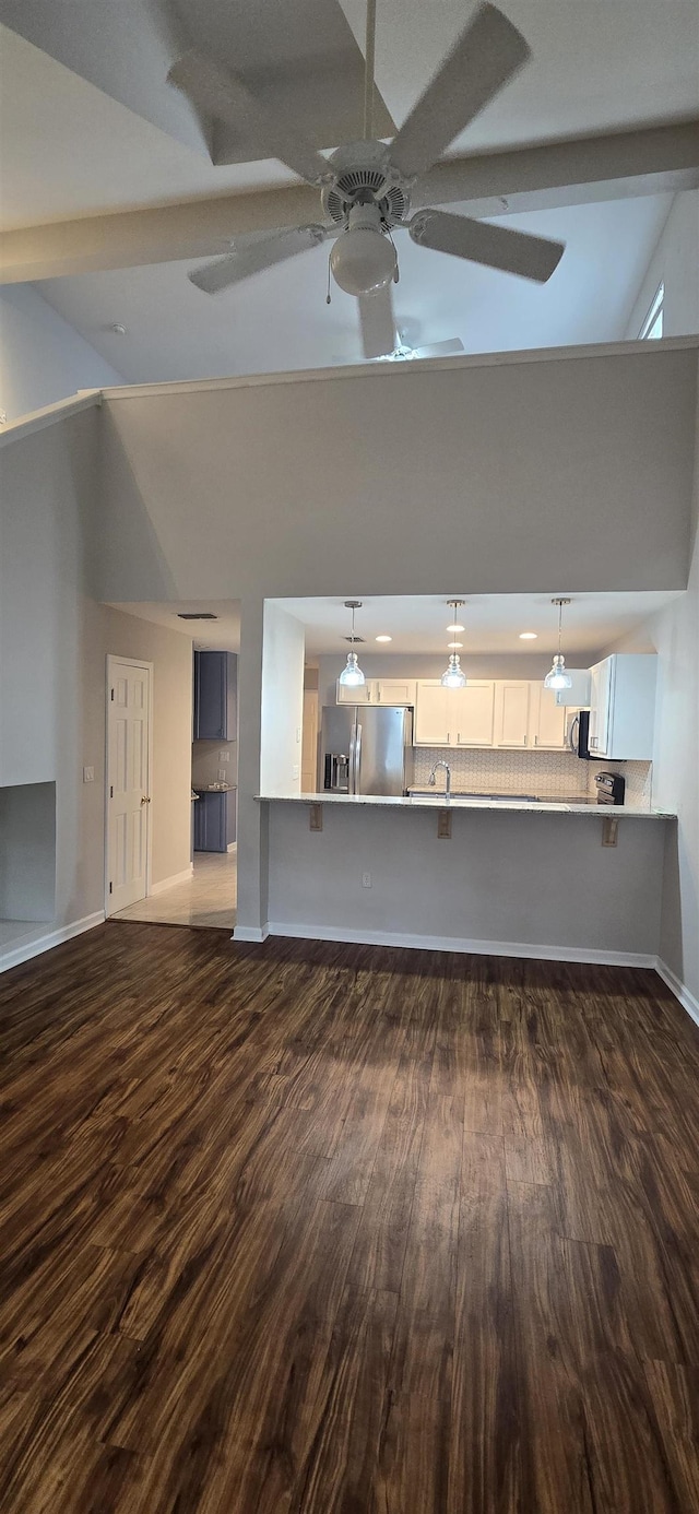 unfurnished living room featuring ceiling fan, dark wood-type flooring, and high vaulted ceiling