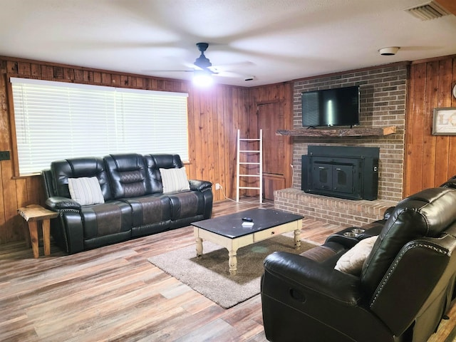 living room with wood walls, ceiling fan, and light hardwood / wood-style floors