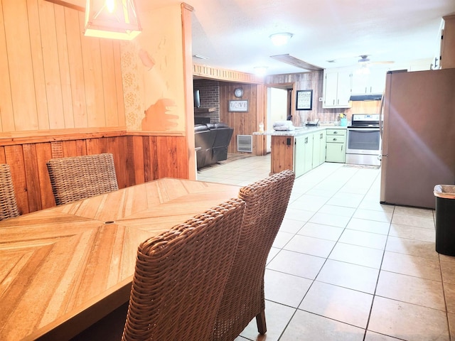 tiled dining space with wooden walls and ceiling fan