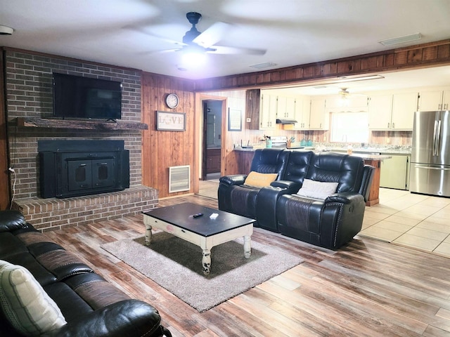 living room featuring wooden walls, a brick fireplace, and light hardwood / wood-style flooring