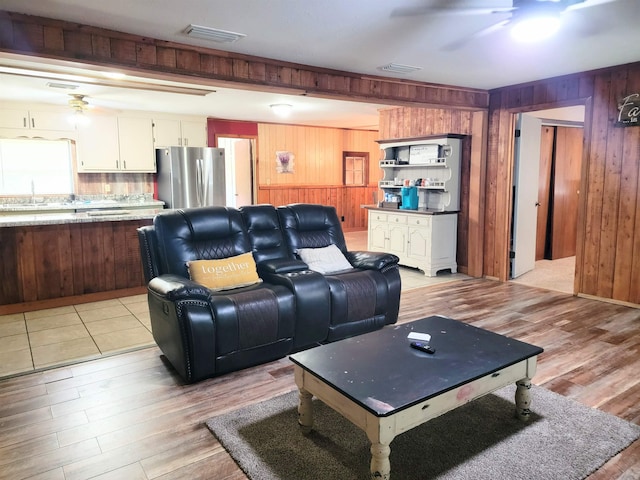 living room with wooden walls, light hardwood / wood-style flooring, and sink