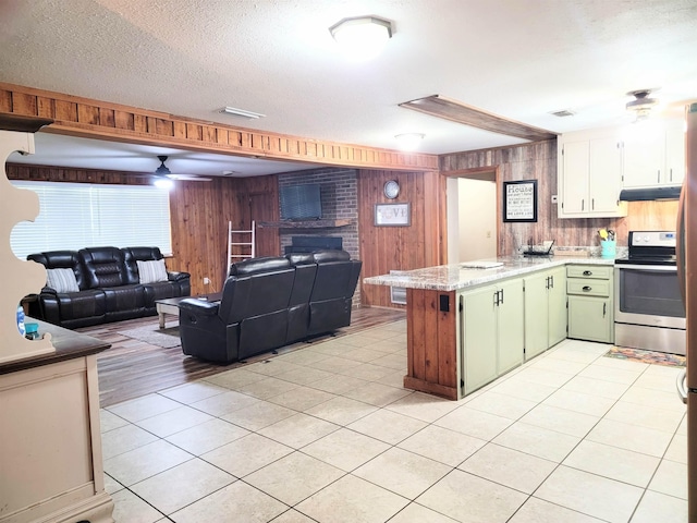 kitchen with green cabinetry, wooden walls, a textured ceiling, light tile patterned floors, and electric stove