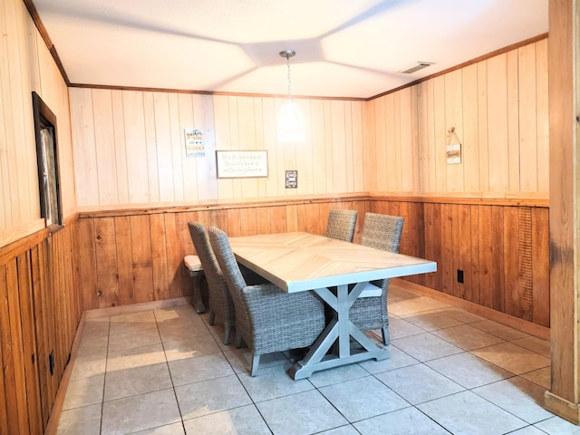 dining area featuring ornamental molding, wooden walls, and light tile patterned floors