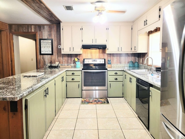 kitchen with stainless steel appliances, green cabinetry, white cabinetry, and light stone countertops