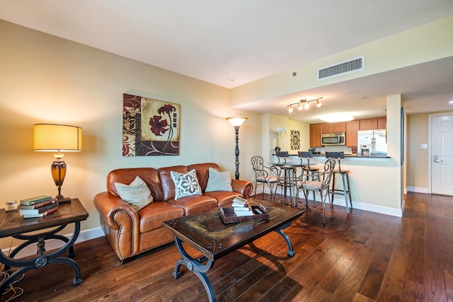 living area with visible vents, dark wood finished floors, and baseboards