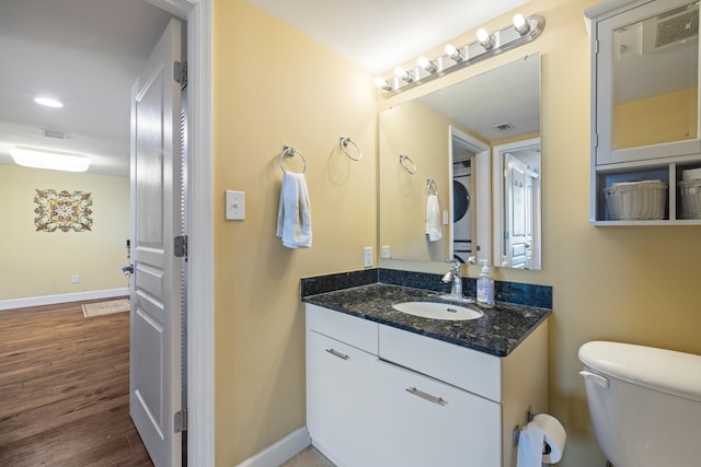 half bathroom featuring visible vents, wood finished floors, vanity, and baseboards