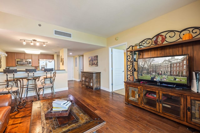 living area featuring baseboards, visible vents, and dark wood finished floors