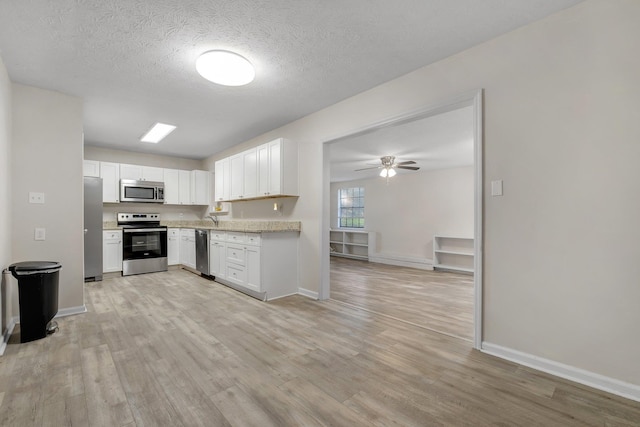 kitchen with white cabinets, light wood finished floors, and stainless steel appliances