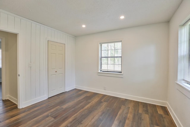 unfurnished bedroom featuring dark hardwood / wood-style floors, a textured ceiling, and a closet