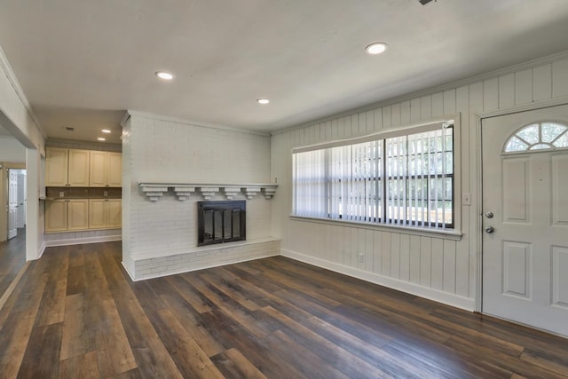 unfurnished living room with a brick fireplace, ornamental molding, and dark hardwood / wood-style floors